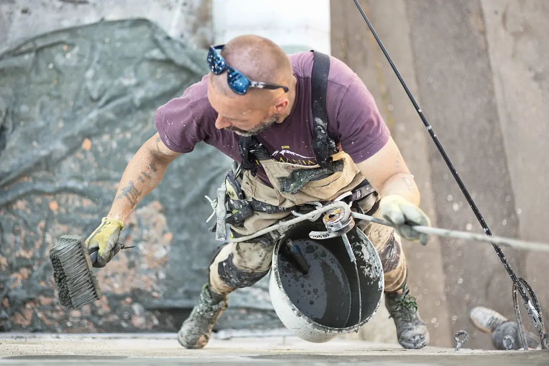 Façadier en cordiste traitant la façade d'un bâtiment en hauteur