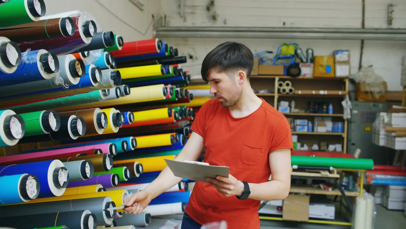 Impression grand format — rouleaux de vinyle adhésif et bâches multicolores en atelier